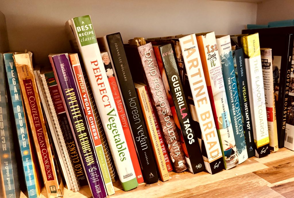 A shelf full of cookbooks, most of them vegan or focused on vegetables.